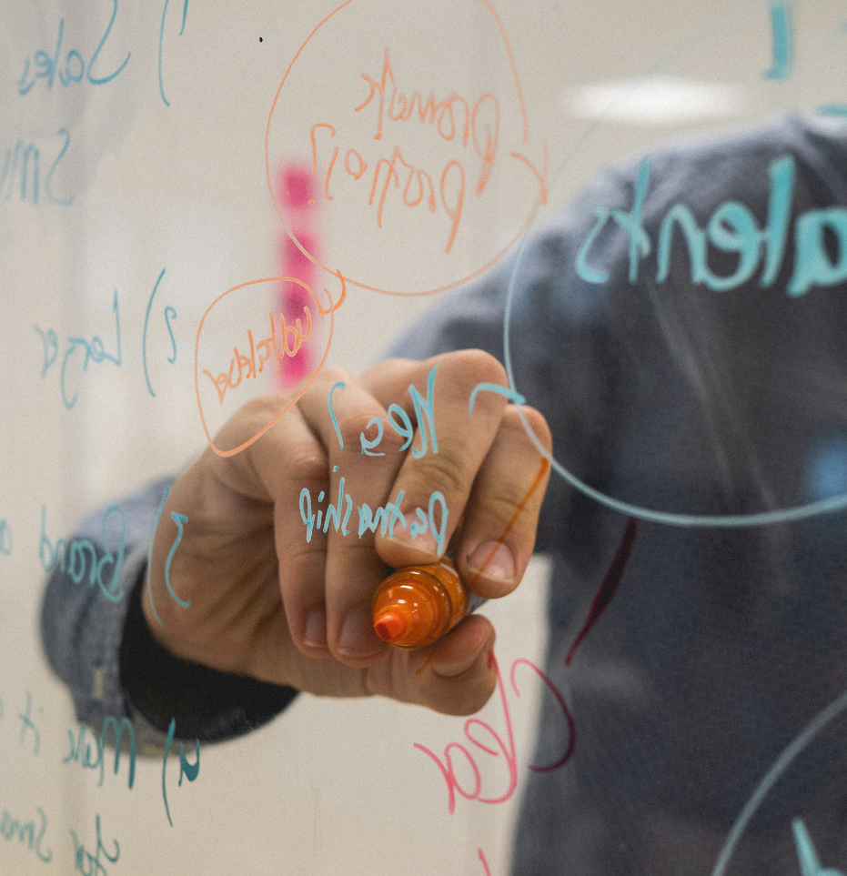 Close up of man making notes on a piece of glass with a whiteboard marker