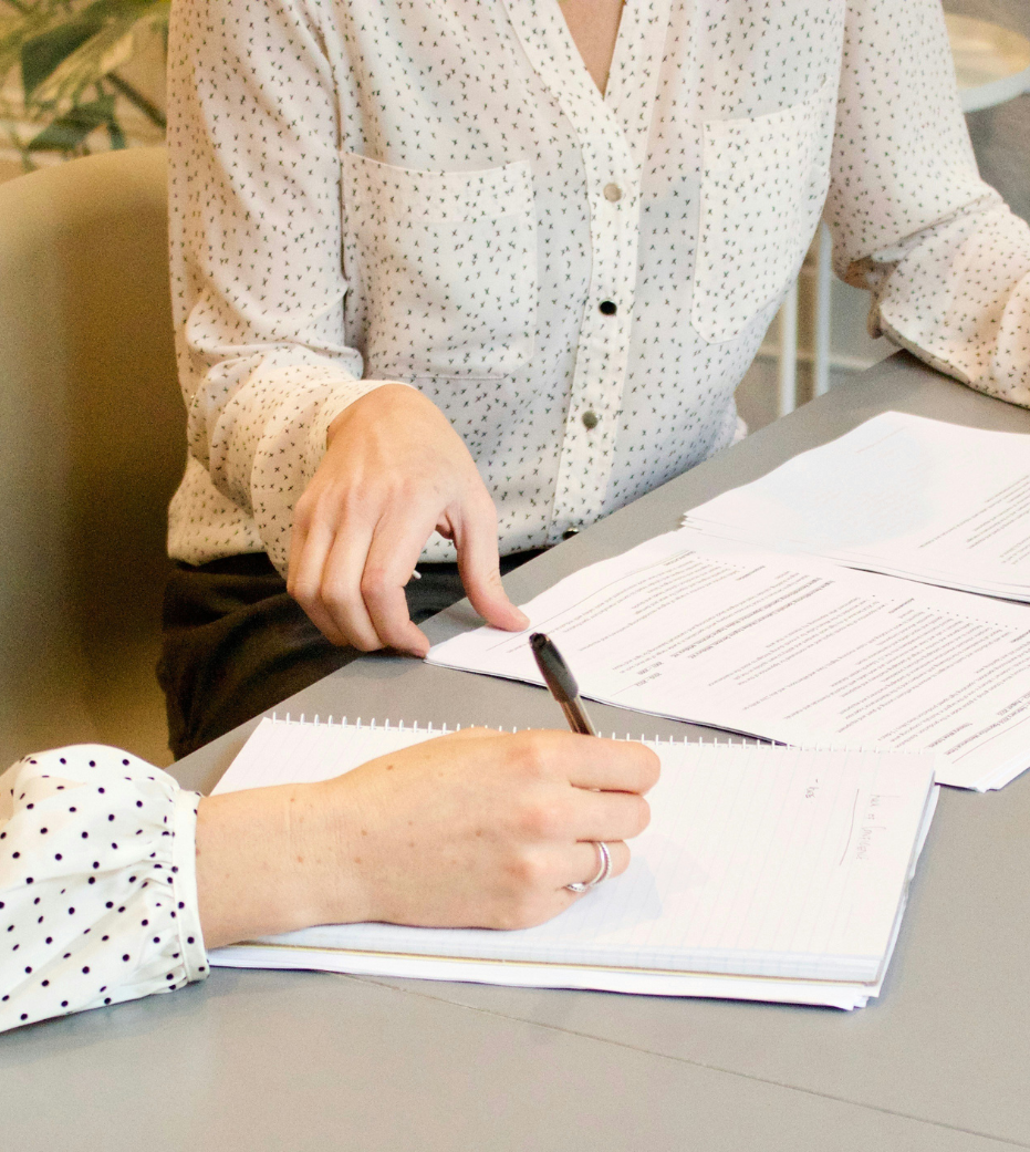 A close up of two women seated at a desk looking at paperwork