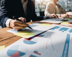 Two business people seated at a table with documents of charts and graphs on table